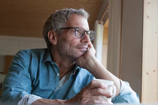 Middle aged man sitting at a table with a coffee mug in his hand