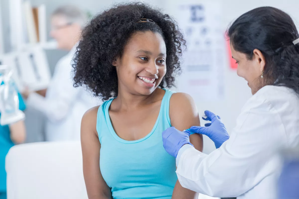 Provider putting a bandaid on a patient after a vaccine