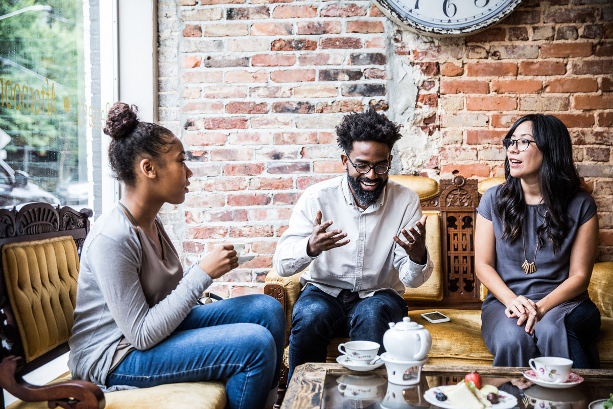 Three people sitting down at a tea shop discussing things