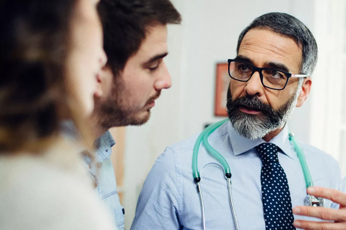 Doctor talking to a patient and their partner in a hallway