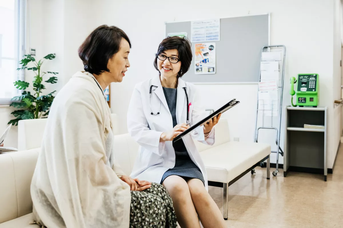 An asain patient is meeting with her doctor in an office