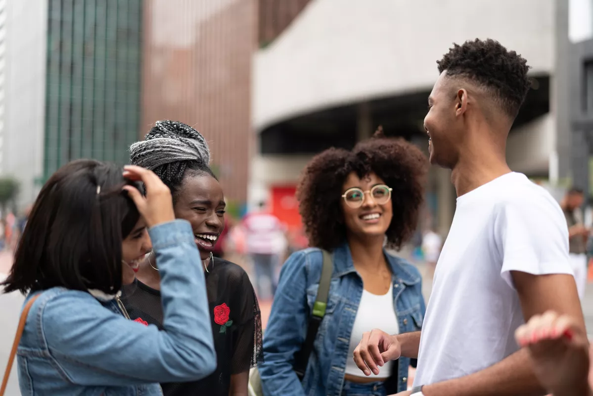 Group of people outside by a building. They are all laughing with each other