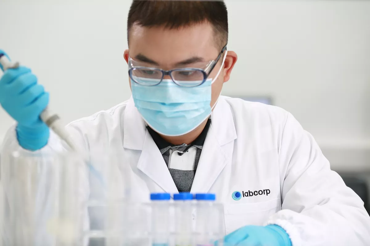 Labcorp Scientist holding a pipette, wearing a mask.