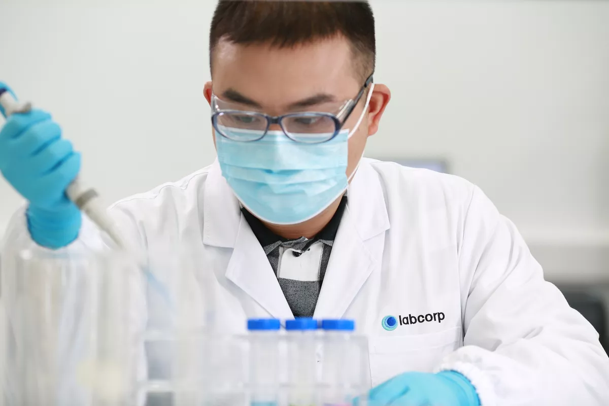 Ein Labcorp-Wissenschaftler mit einer Maske und einer Pipette in der Hand