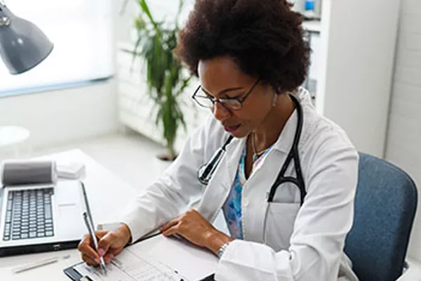 Provider writing notes at her desk