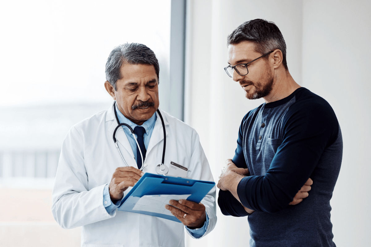 Provider and patient standing in exam room talking over a chart