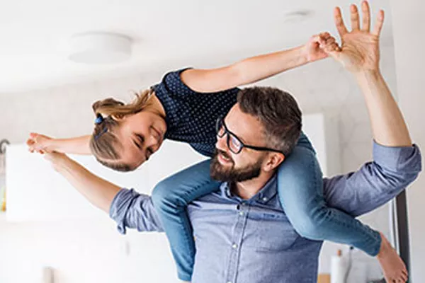 father with daughter on his shoulders. She is holding his hands