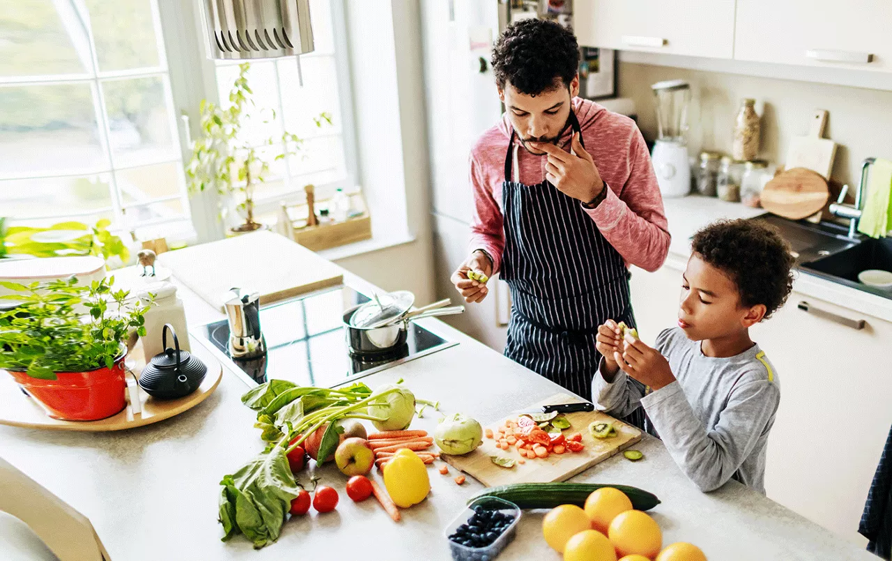 Father and son prepping and eating food in a kitchen