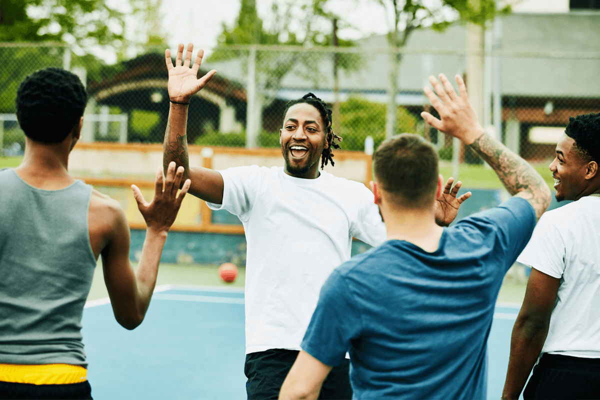 Group of men playing a game of basketball. They are high-fiving each other