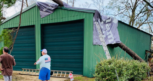 Fallen lamar advertising billboard vinyl on shed with debris after storm