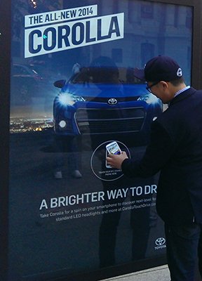 Man using mTAG mobile test-drive feature on Toyota Corolla advertisement on Lamar Advertising inventory