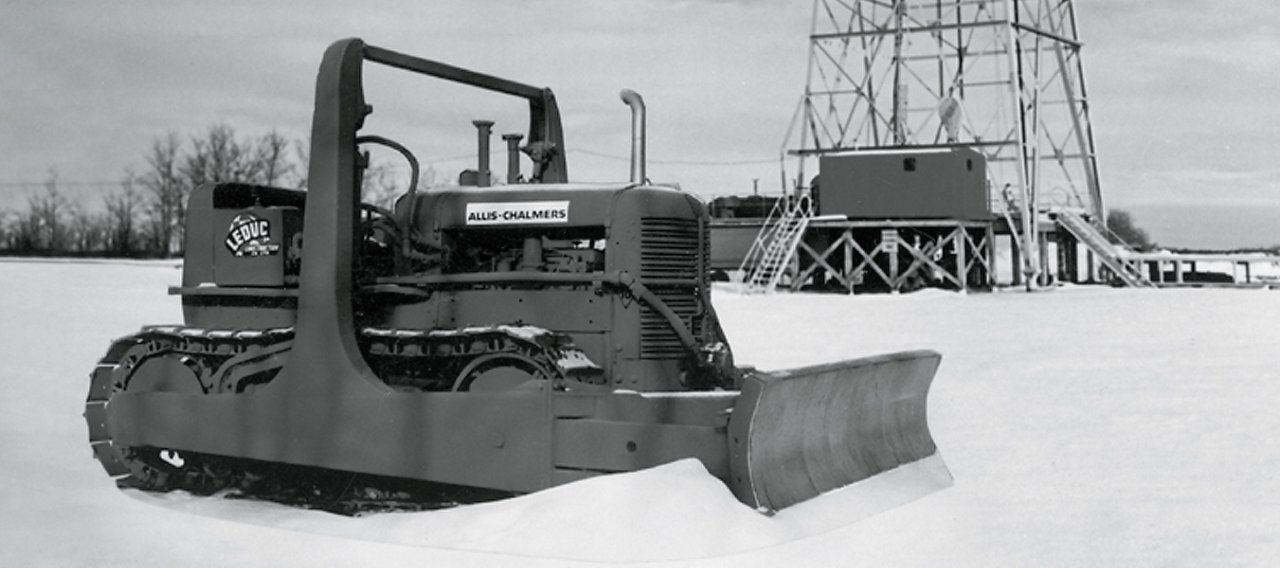 Bulldozer in snow sitting in front of large tower