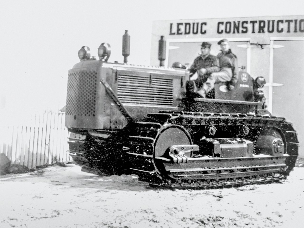 Two guys riding on old tractor