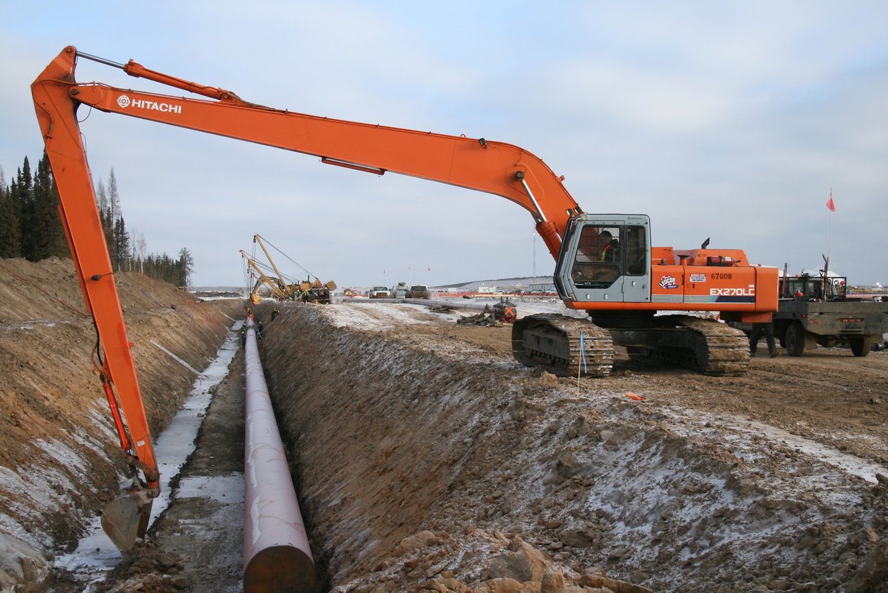 Excavator moving pipe into ditch
