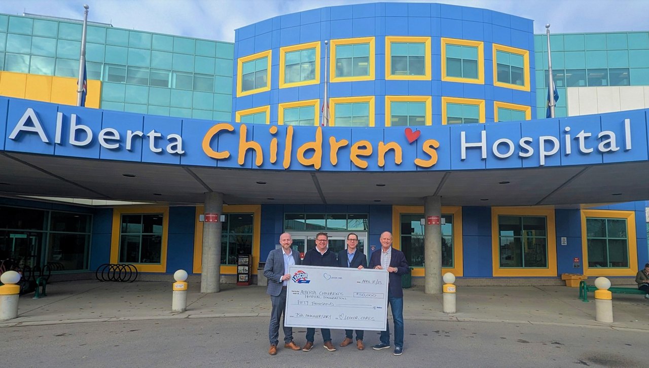 A group of people pose in front of the Alberta Children's Hospital with a large cheque