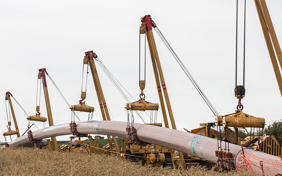 Cranes holding and installing pipes.