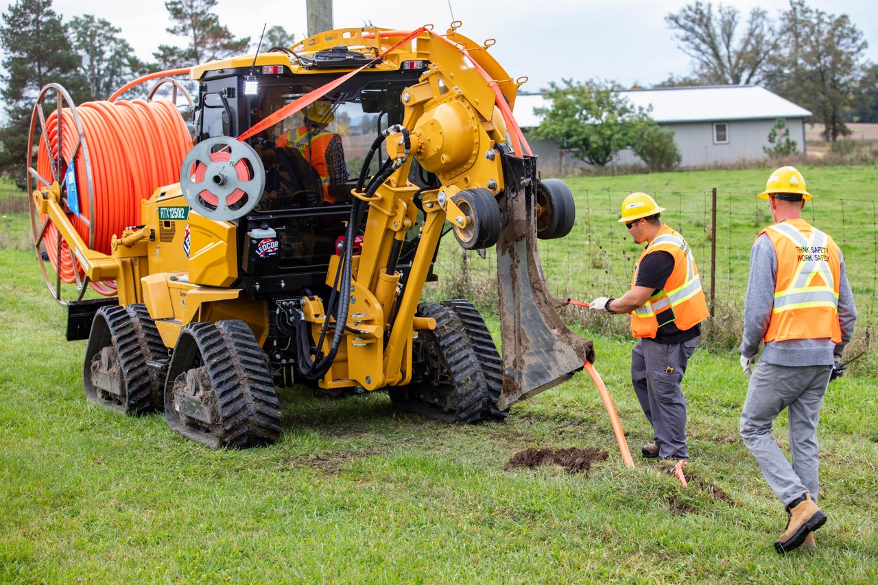 Men following behind machine laying down flexible pipe