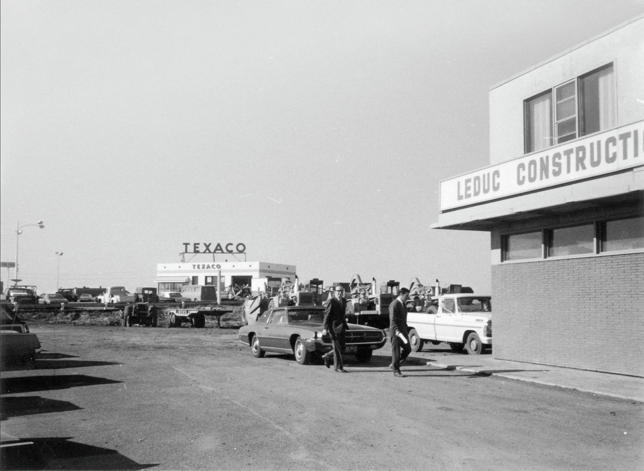 Old image of cars parked infront of a gas station and building