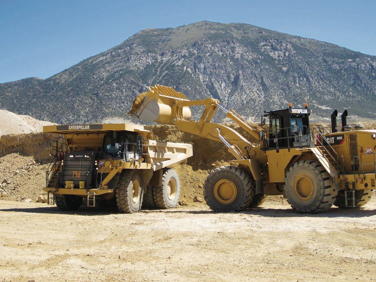 Bulldozer dumping soil in Truck.