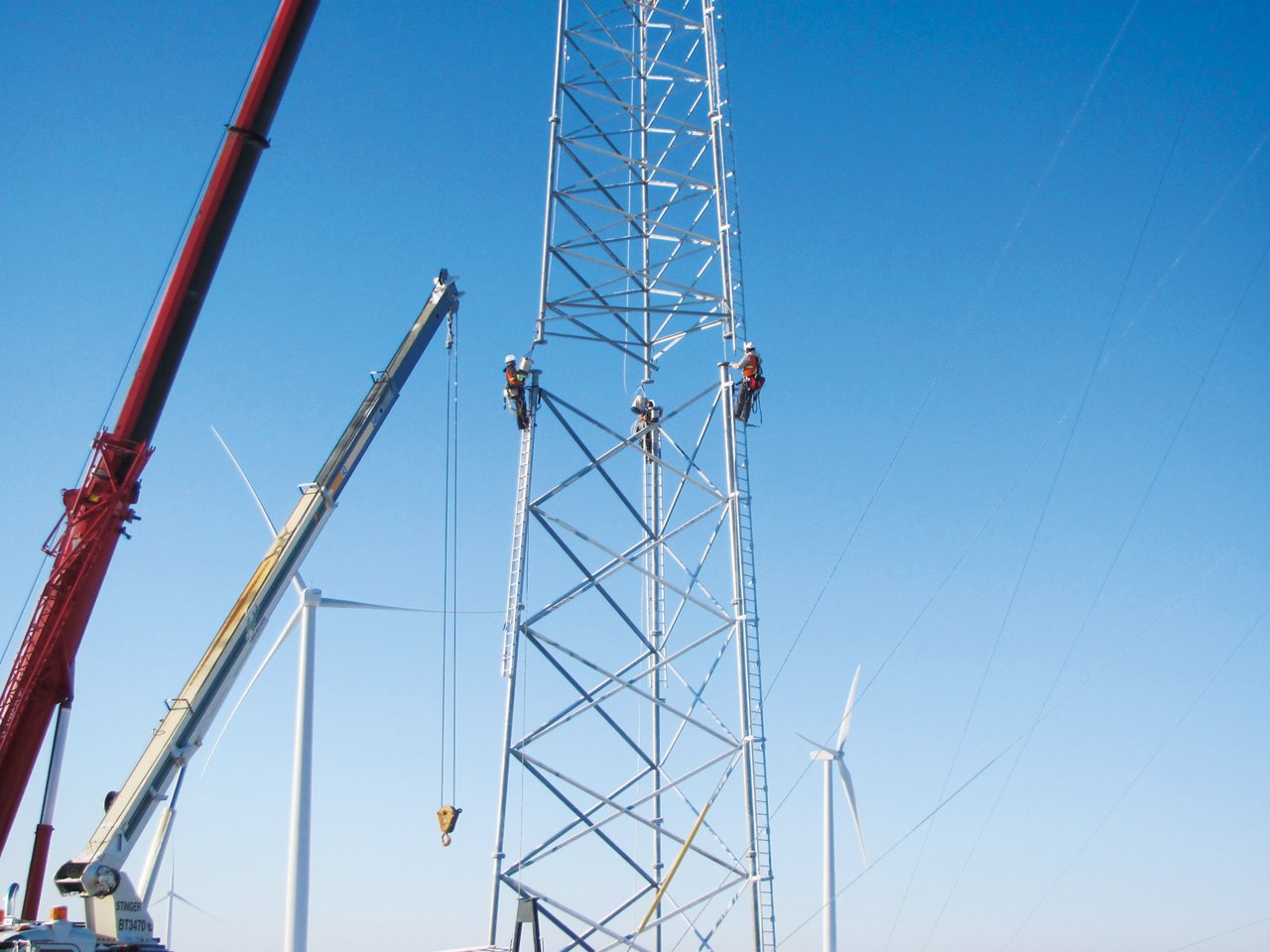 men on large tower mounting next section of radio tower