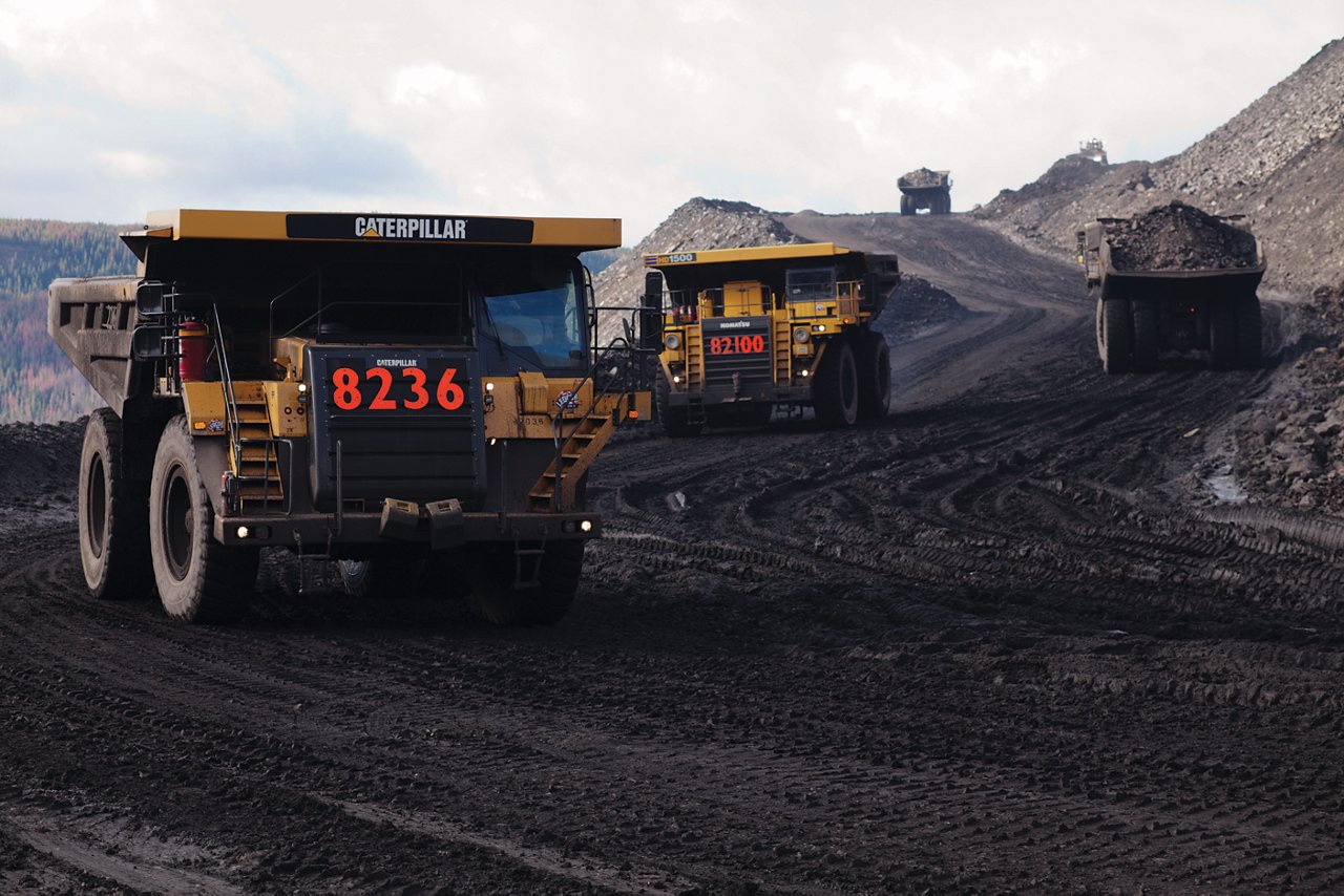 Large dump trucks travelling down dirt road