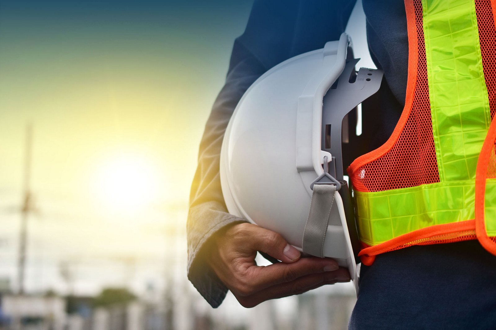 A close-up photo of a laborer holding a hardhat