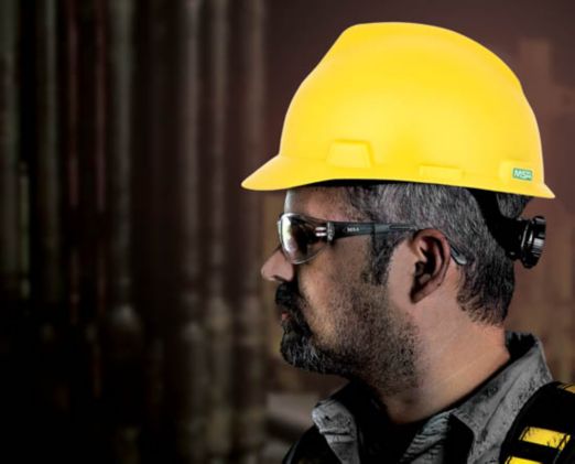 A profile view of a construction worker wearing a yellow matte V-Gard hard hat