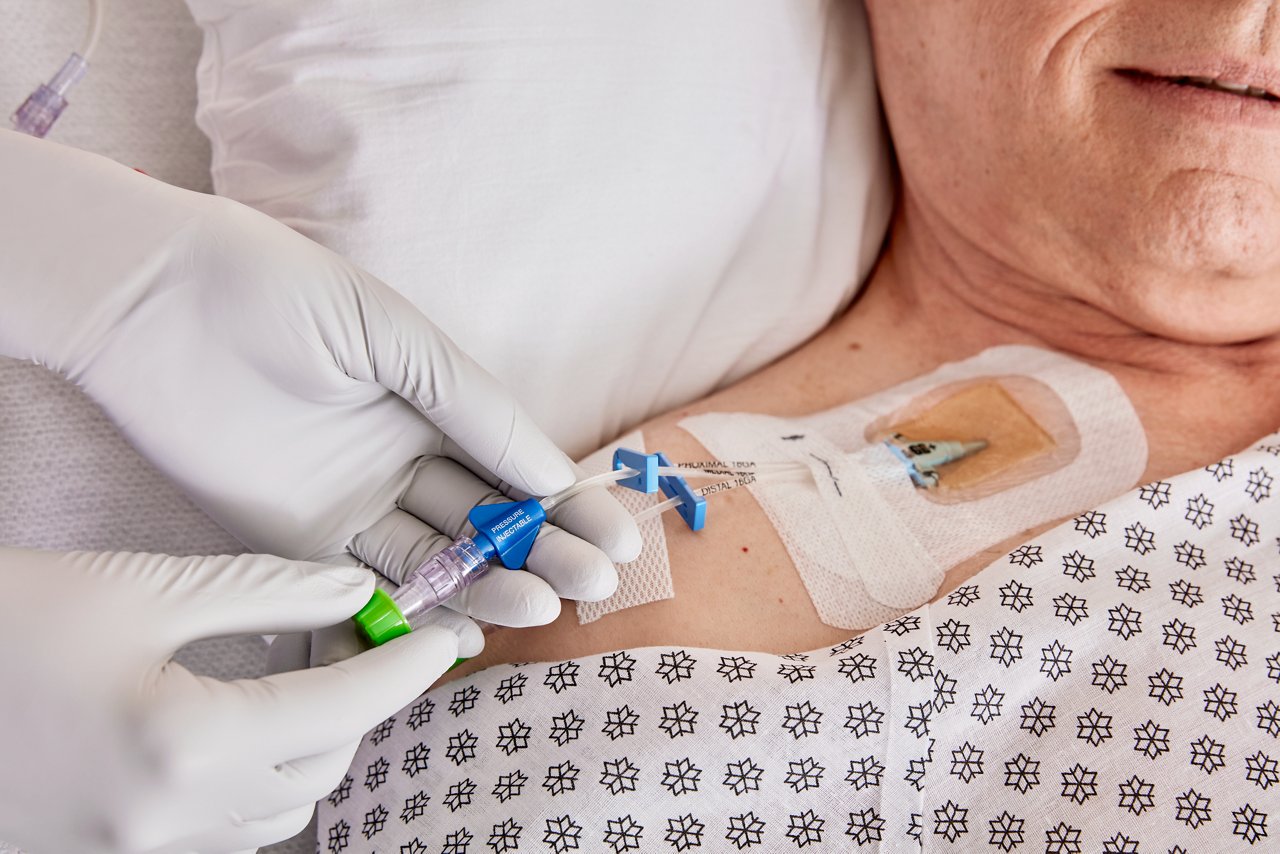 3M™ Tegaderm™ CHG Dressing 1657 + Curos™ Cap Application Image - featuring male ICU patient in hospital room with nurse accessing IV line