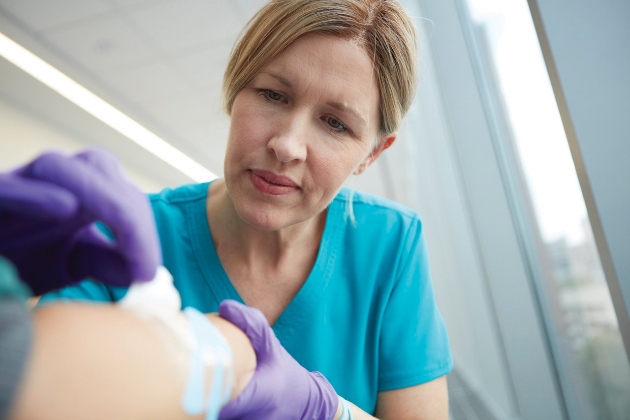 3M™ Tegaderm™ Schaumstoffverband Produktbroschüre - Wundversorgung Lifestyle Hintergrundbild - Arzt entfernt Verbände vom Arm des Patienten