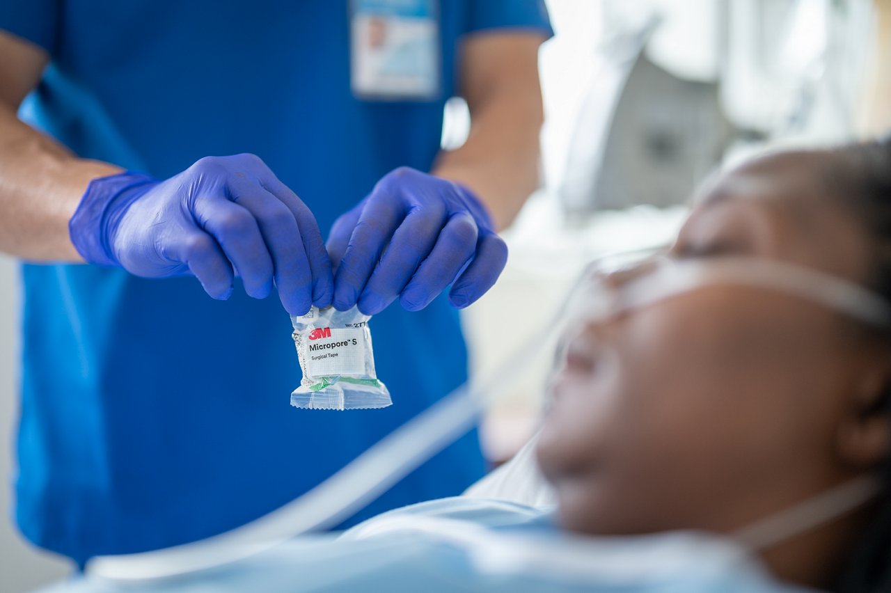 Patient im Krankenhaus mit Pflegepersonal, das Micropore S medizinisches Rollenpflaster auf die Infusionsleitung anbringt