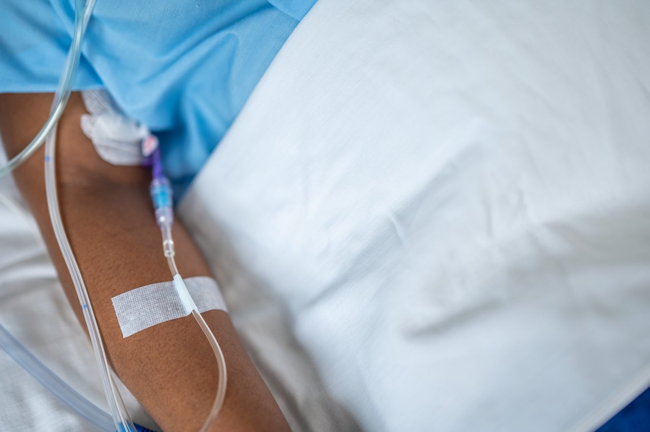 Patient in hospital with nursing staff  applying Micropore S medical tape to IV line