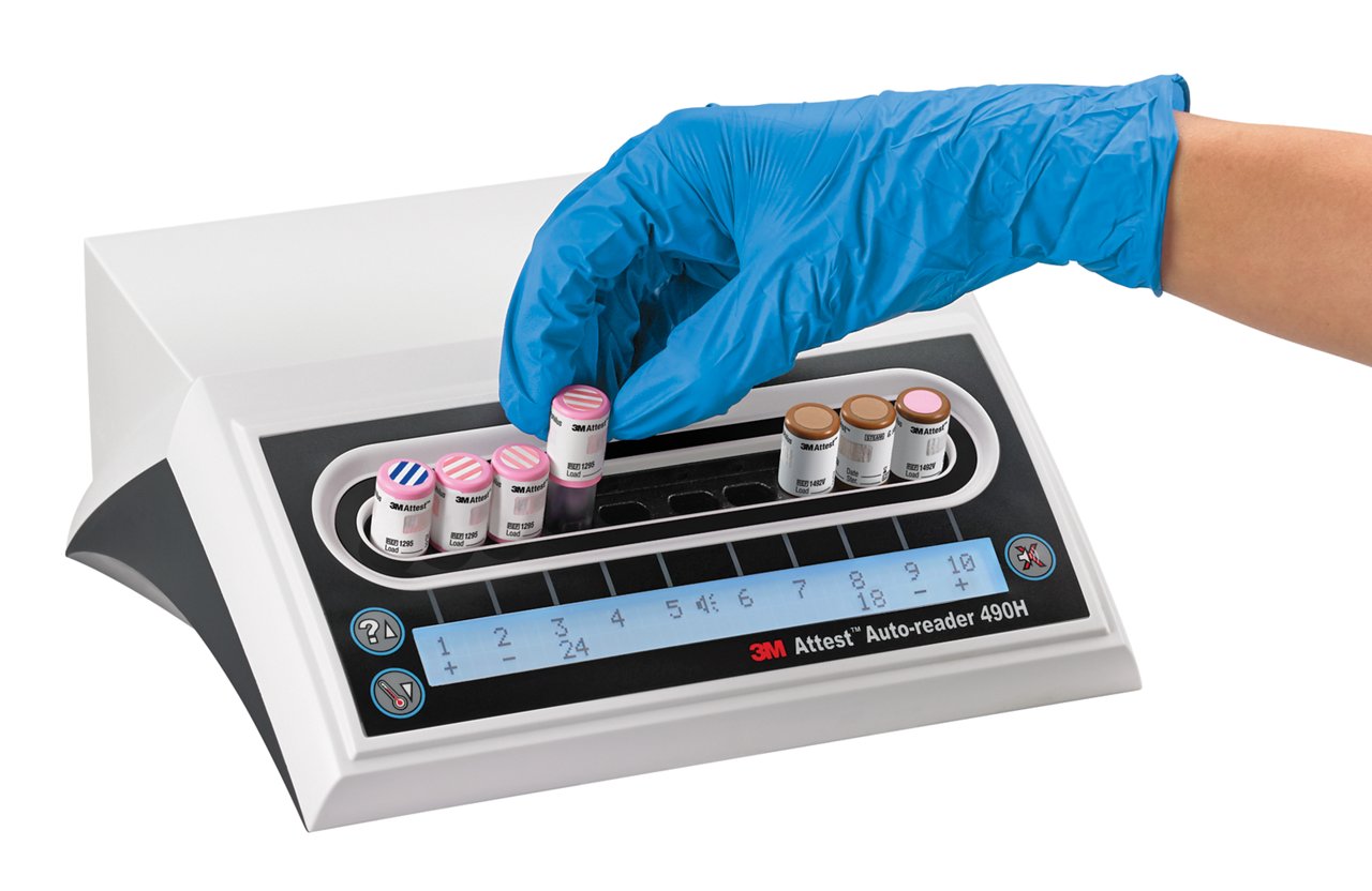 淺藍色手套的手插入3M™ Attest™ 快速讀數生物指示劑1295至3M™ Attest™ 自動讀取器490H。