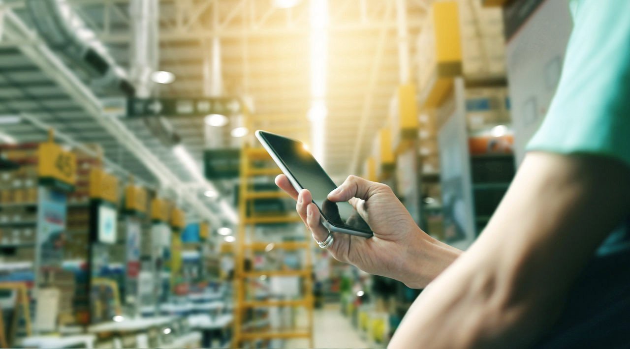 Factory worker using application on mobile smartphone to operate automation for modern trade.