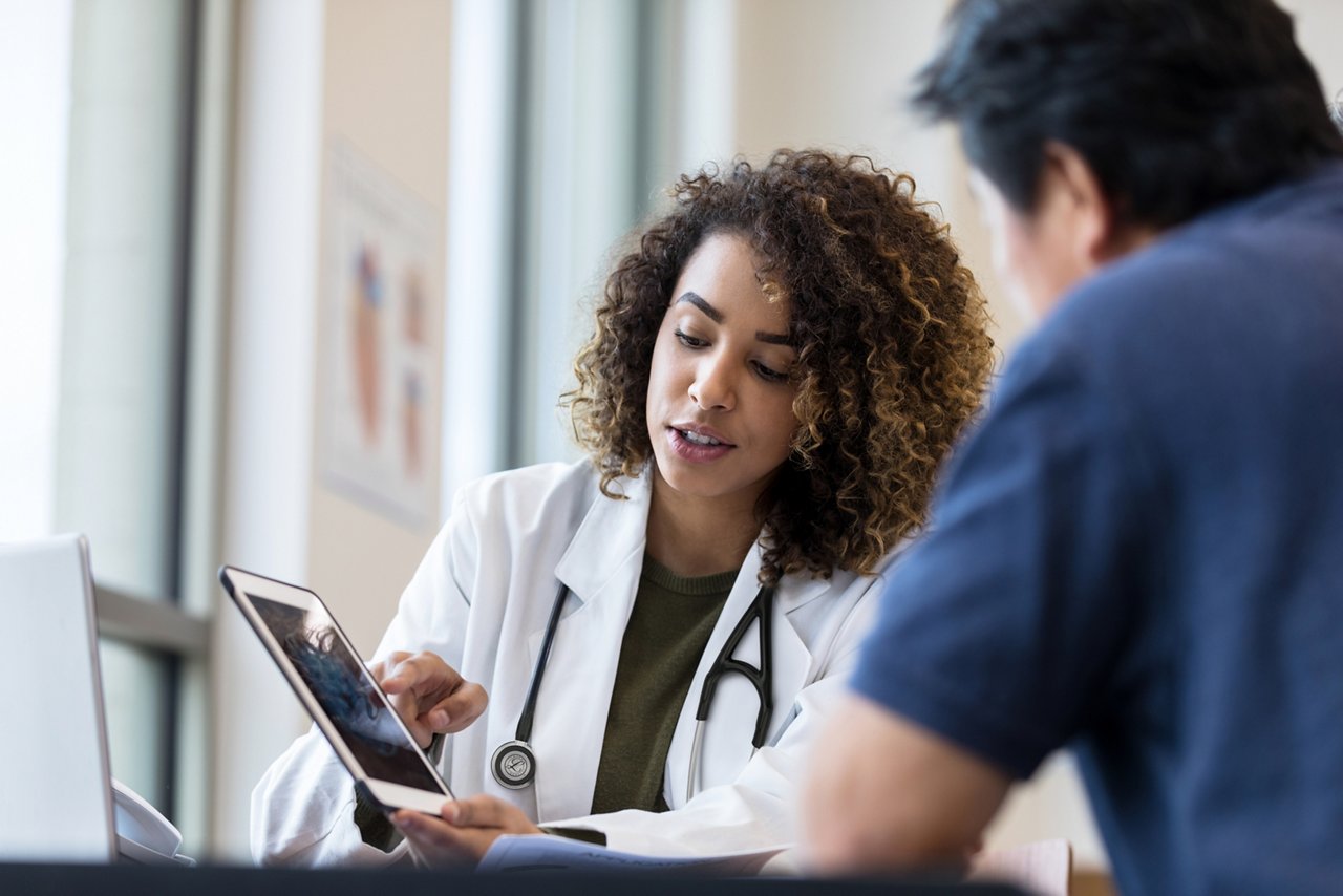 A doctor pointing out information on a tablet to a colleague.