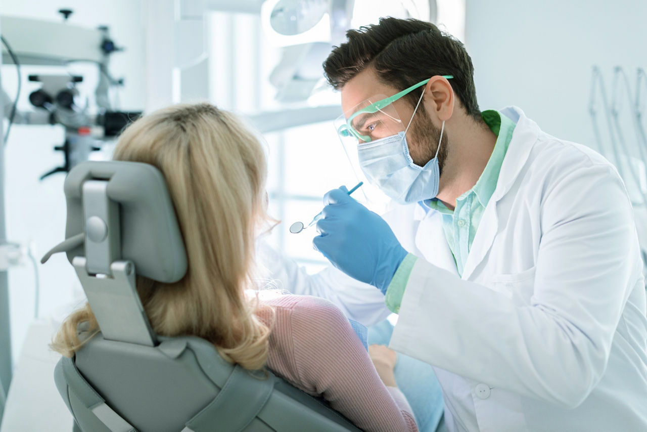 Hombre dentista con mascarilla y gafas haciendo un tratamiento, Ucrania