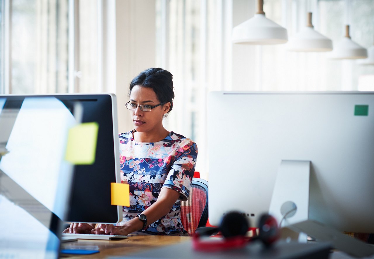 A woman focuses intently on the computer monitor in front of her.