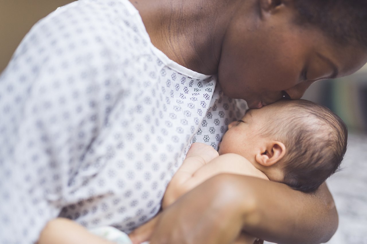 A mother kissing her newborn's forehead.