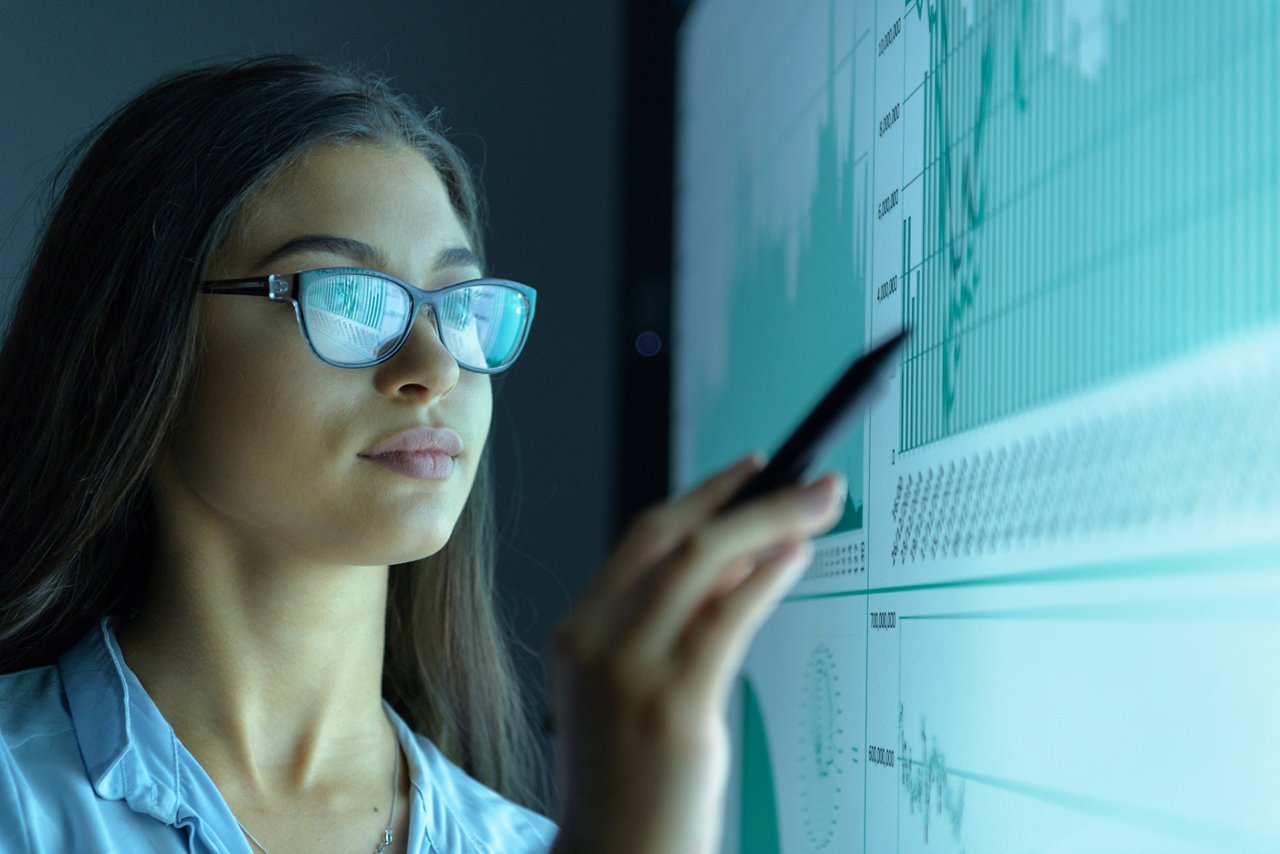 A woman pointing to a graph projected onto a screen.