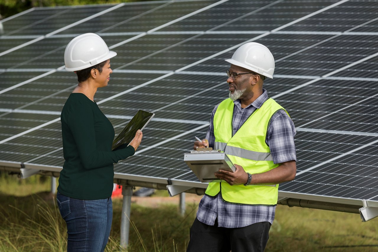 The mature adult female engineer and the mature adult male tech discuss the the solar panel installation.