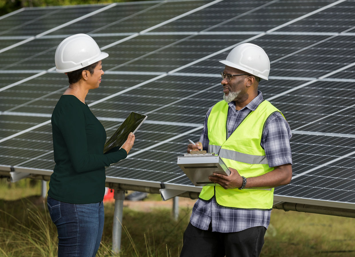 The mature adult female engineer and the mature adult male tech discuss the the solar panel installation.