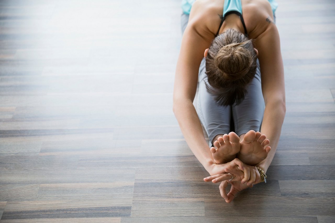 Woman in a forward bend sitting practicing mudra yoga
