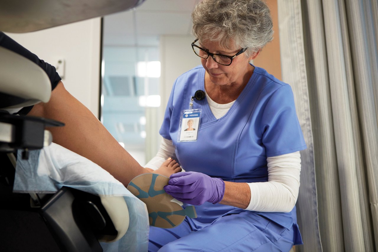 Product Brochure 3M™ Tegaderm Foam Dressing 3M Tegaderm™ - lifestyle image of wound care, clinician applying dressing to patient's heel and foot