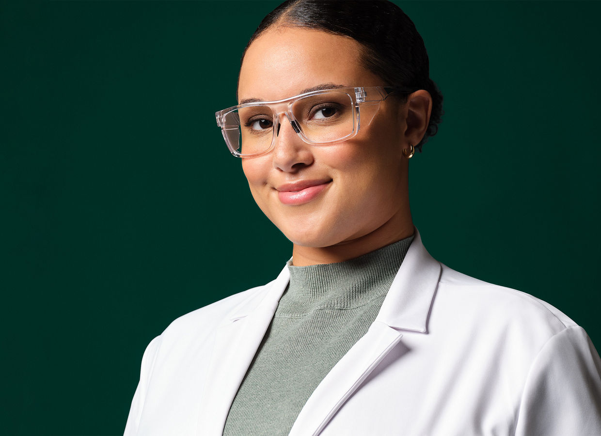 Ingeniera de aplicaciones femenina usando bata de laboratorio blanca, gafas de seguridad y guantes azules.