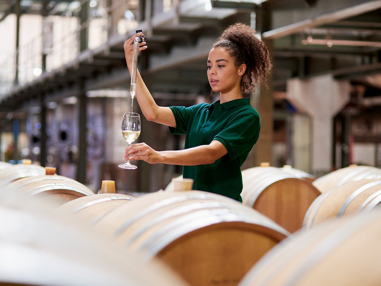 Young woman testing wine in a wine factory warehouse