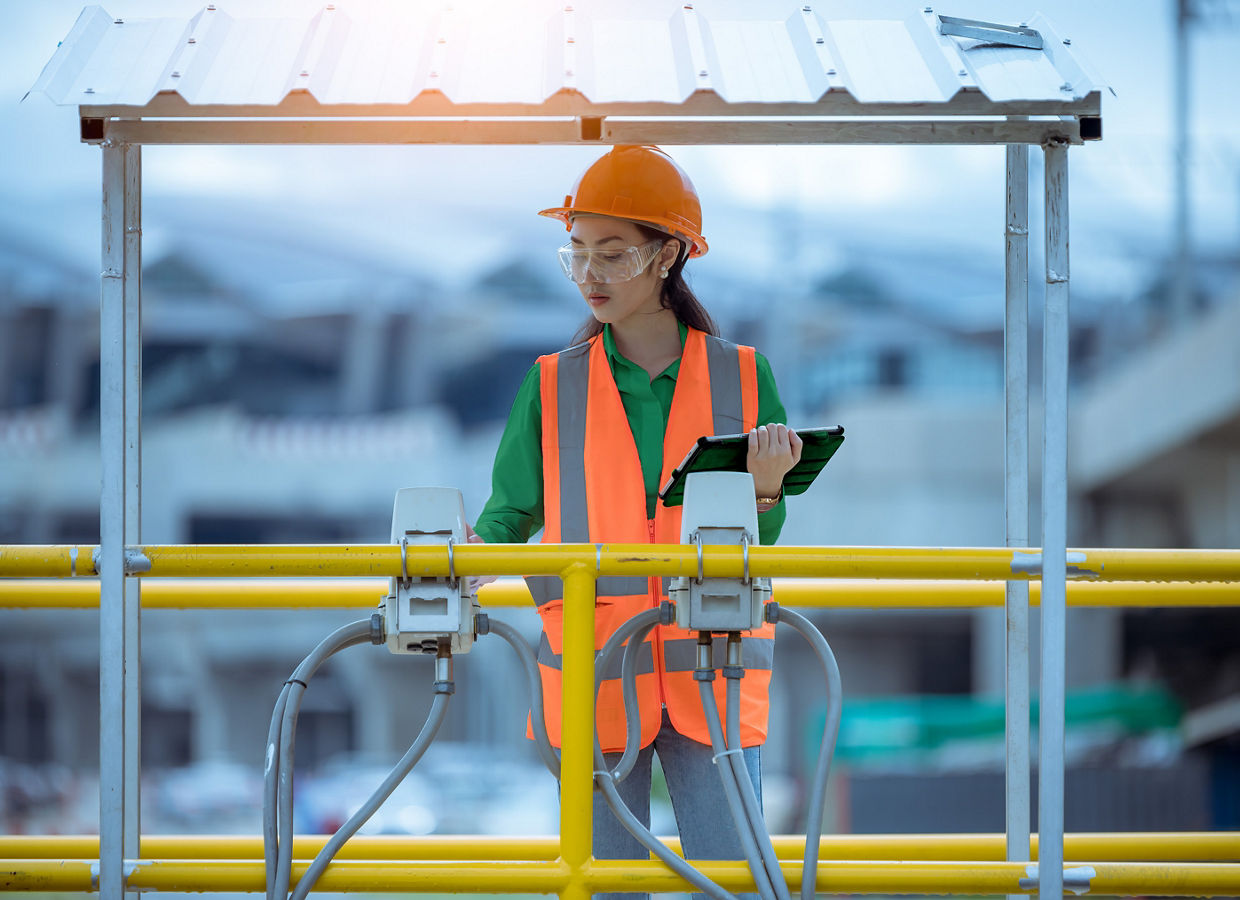 水質をチェックするため、廃水処理池から水を採取する女性作業員。