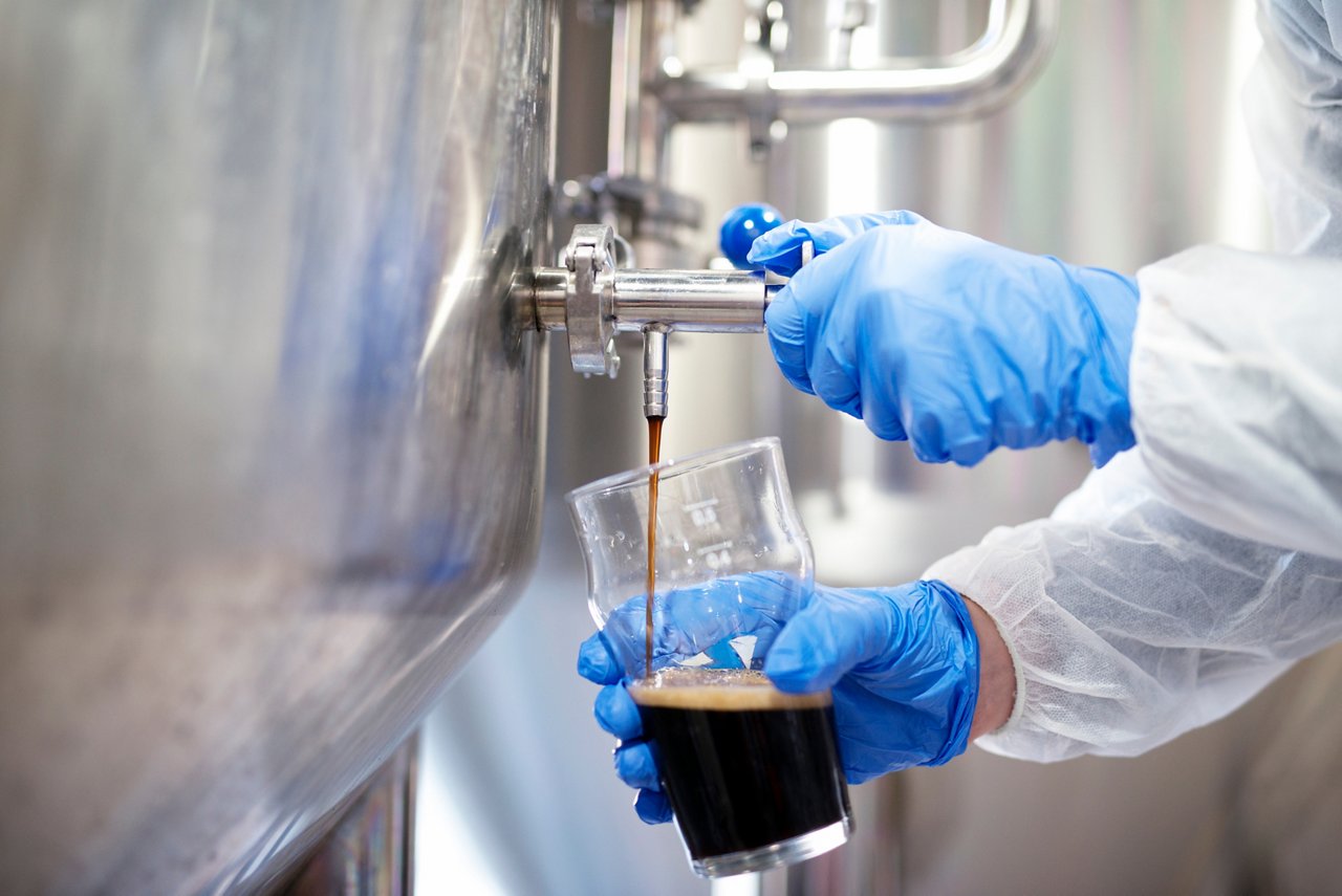 This asset is Shutterstock ID 1289427586. This is licensed from Shutterstock Images. Unlimited seats were licensed there is no charge to use this image. Please download and use as needed, but relate this asset to the final assets utilizing this image. Title: Close up of beer filling glass at brewery. Beer pouring out of tap reservoir tank. Quality control by technologist.