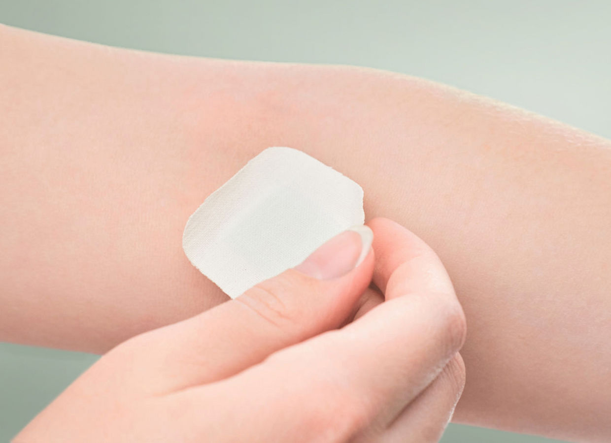 The girl sticks a patch on the elbow after giving blood from a vein. Concept for hospitals, laboratories, donation support