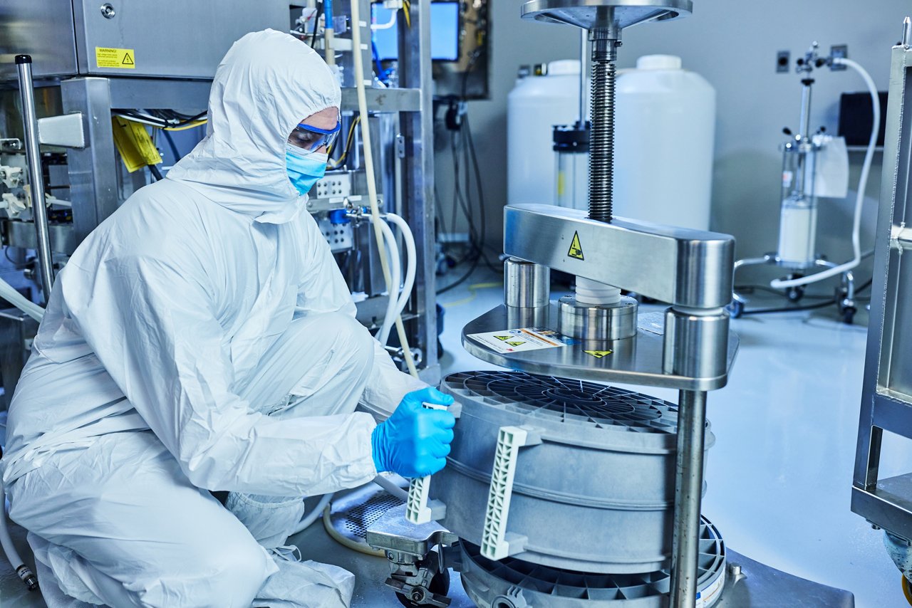 Man in clean room suit loads product into holder
