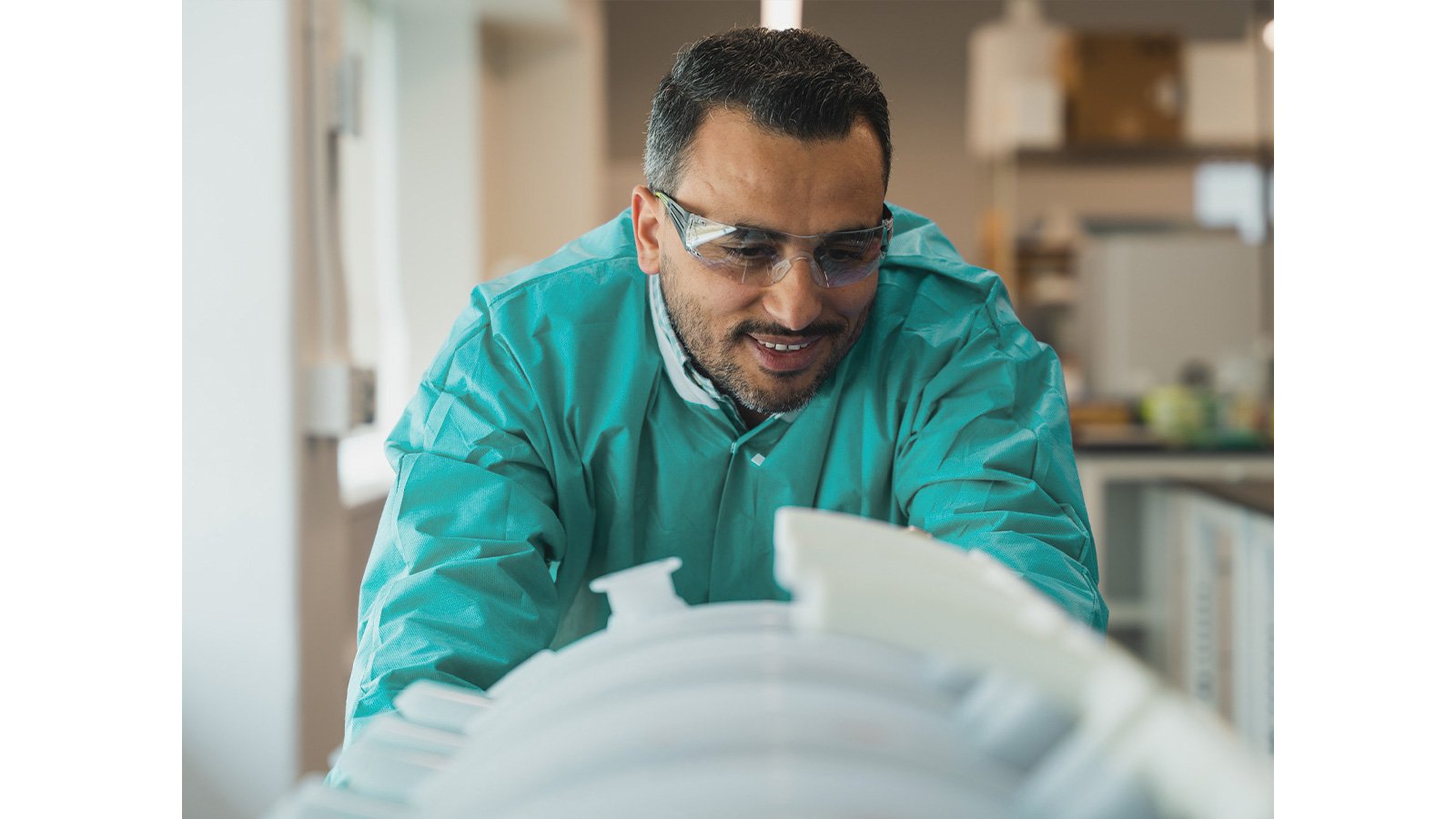 Process engineer in green lab coat looks at product