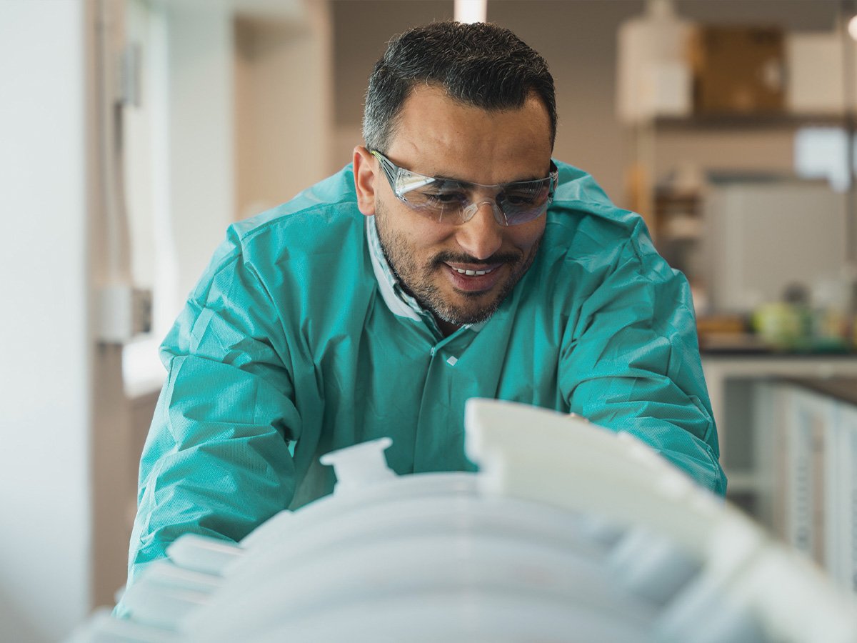 Process engineer in green lab coat looks at product